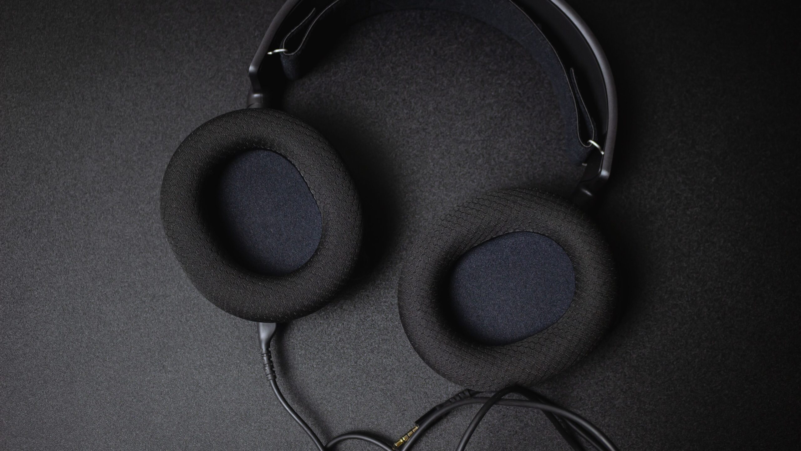 Best Gaming Headsets for PC (2026) 2 Black gaming headset with a detachable audio cable on a dark desk
