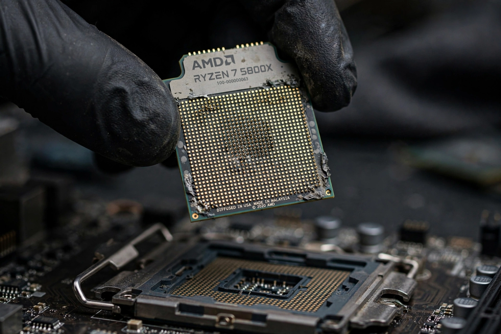 A used AMD Ryzen CPU held above a motherboard socket for inspection